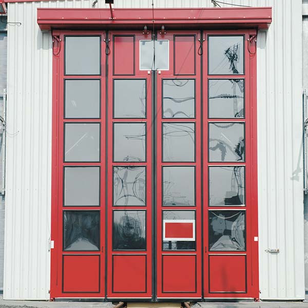 Rote STRICKER Falttoranlage in weißer Halle eingebaut.