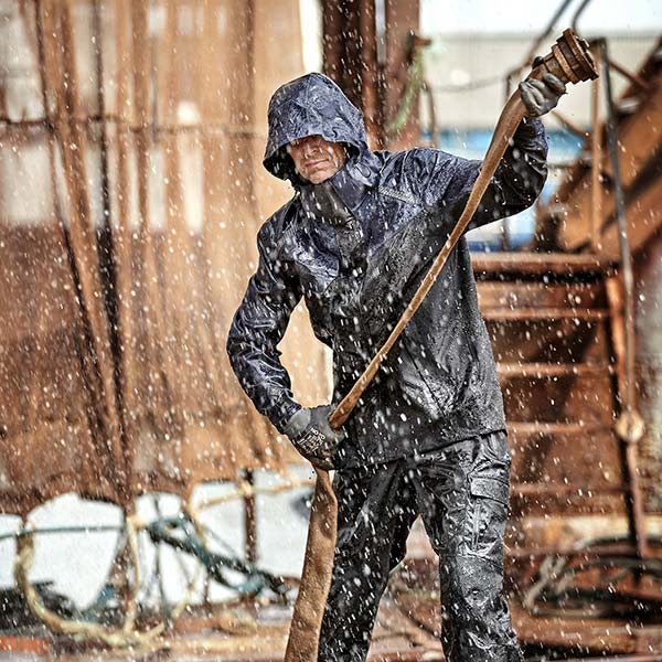 Blick auf eine Person, welche Wasserspritzer ab bekommt allerdings durch die Regenschutzkleidung von STRICKER geschützt ist.