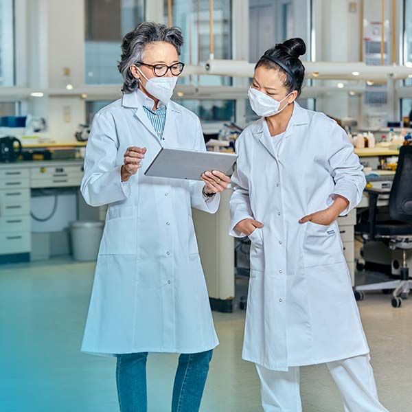 Blick auf zwei Frauen im Labor, welche weiße Kittel tragen. 