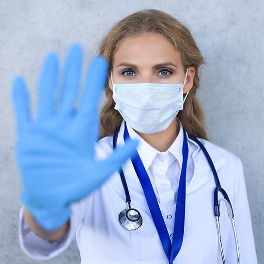 Blick auf eine Ärztin, welche die Hand ausstreckt und Ihre Enweghandschuhe zeigt.