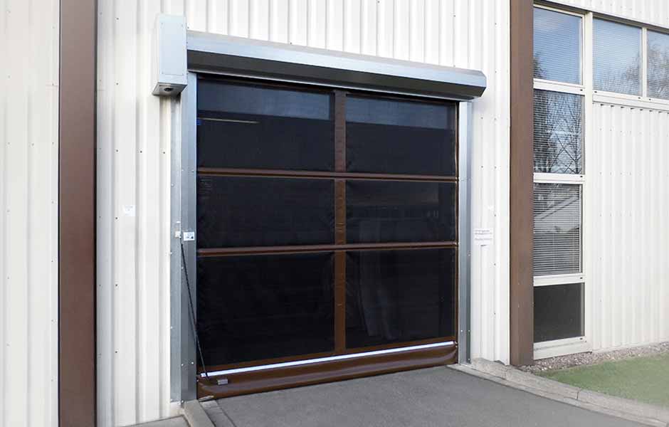 Eingebautes Insektenschutztor als Eingang zu einer Halle. Das Insektenschutztor hat braune Rahmen und schwarze Fliegengitter.